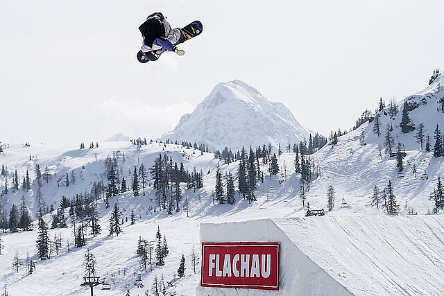 Am Bild sieht man einen Snowboarder beim Jump auf einem Flachau gebrandeten Obstacle