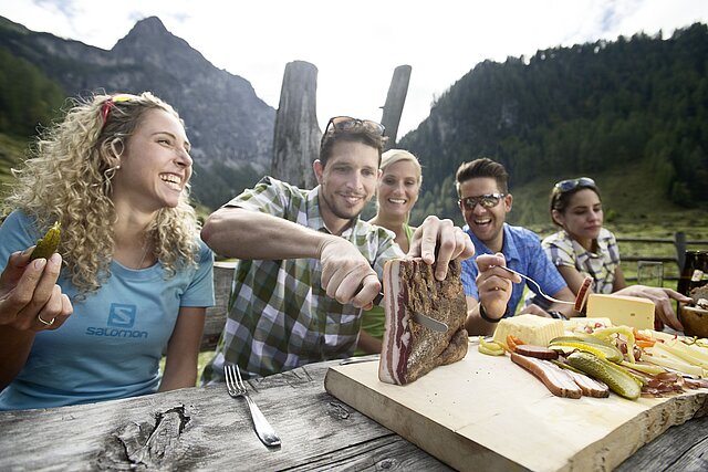 Friends having a "Brettljause" on an alpine pasture.